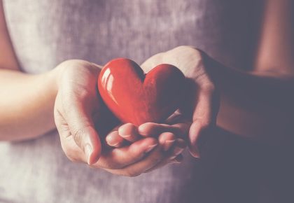 Picture of Girl holding heart in the page Why we should seek happiness through helping others